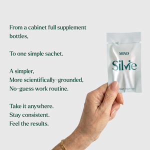 A hand holds a small silver supplement sachet labeled 'MIND Silvie' against a light gray background with dark green promotional text describing a simplified supplement routine.