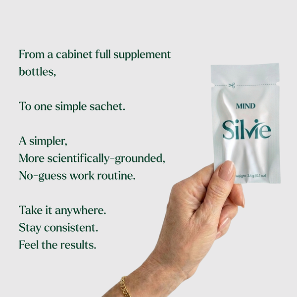 A hand holds a small silver supplement sachet labeled 'MIND Silvie' against a light gray background with dark green promotional text describing a simplified supplement routine.