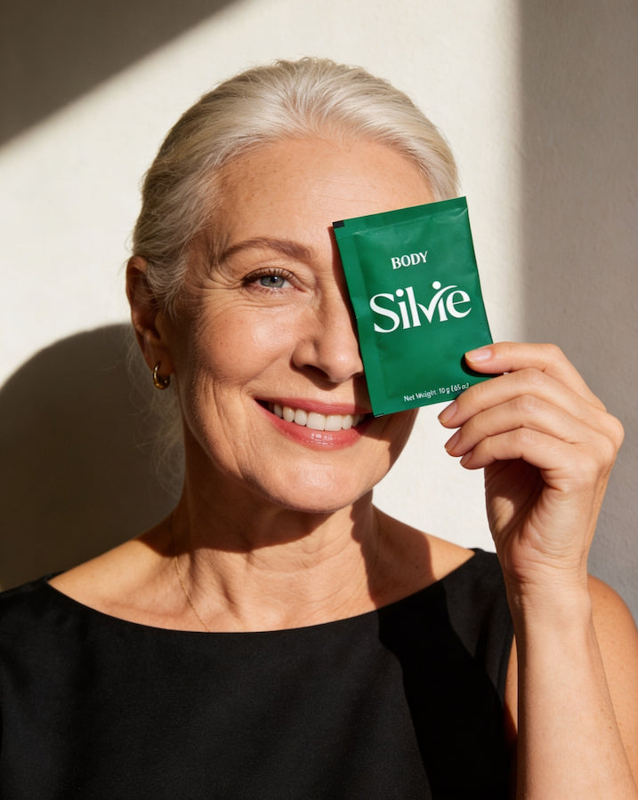Woman over 55 holding a Silvie Body daily powder sachet